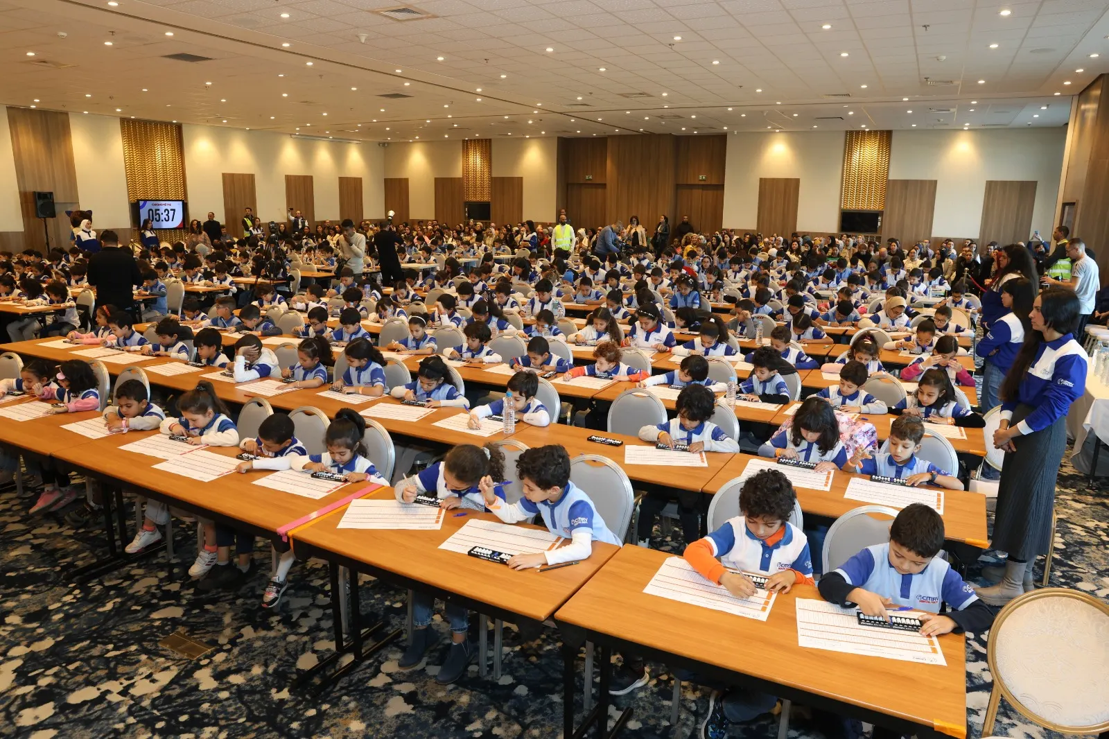 Grande salle de compétition remplie de centaines d'enfants concentrés sur leur boulier